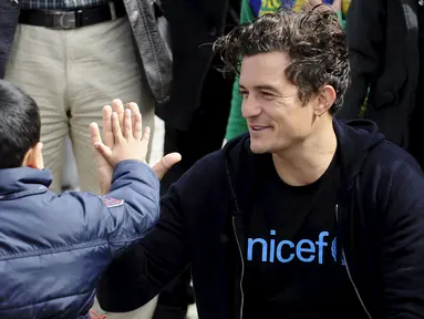 Duta UNICEF, Aktor Orlando Bloom melakukan tos dengan seorang anak  saat mengunjungi kamp transit migran di Gevgelija, Makedonia, 29 September 2015. (REUTERS/Ognen Teofilovski)