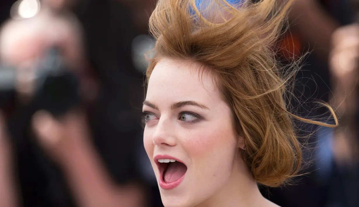 Rambut Emma Stone yang sudah tertata rapi tampak tertiup angin saat berpose jelang pemutaran film Irrational Man, di Festival Film Cannes di Perancis, Jumat (15/5/2015). (REUTERS/Yves Herman)