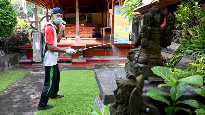 Seorang petugas kesehatan menyemprotkan disinfektan di kawasan wisata di Sanur, Bali, Senin (16/3/2020). Penyemprotan dilakukan sebagai salah satu langkah untuk mengantisipasi potensi penyebaran virus Corona COVID-19 di kawasan pariwisata tersebut. (SONNY TUMBELAKA/AFP)