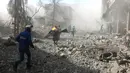 Penyelamat berlari untuk membantu korban serangan udara pasukan pemerintah di Ghouta Timur, Damaskus, Suriah, Selasa (20/2). Kelompok pemantau dan paramedis Suriah mengatakan serangan itu menewaskan 98 orang. (Syrian Civil Defense White Helmets via AP)