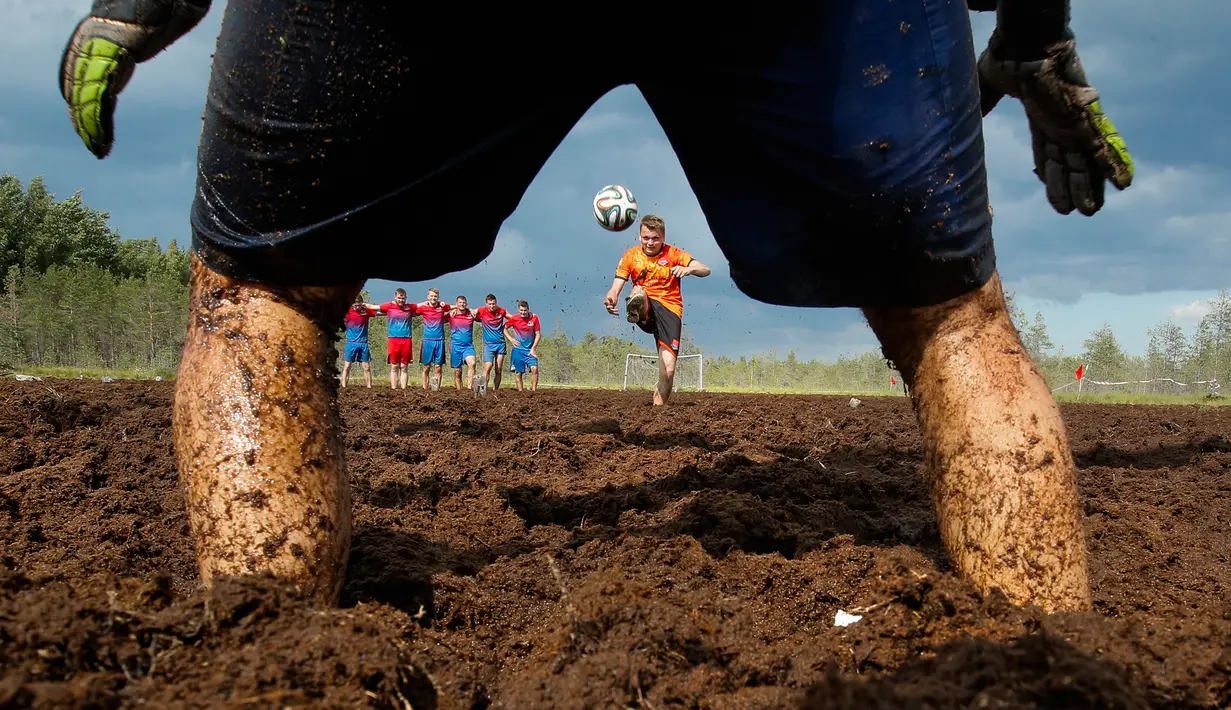 Seorang pemain sepak bola rawa melakukan tendangan penalti dalam turnamen sepak bola rawa di desa Pogy, 60 km (37 mil) dari St. Petersburg, Rusia pada 22 Juni 2019. Meski lumpur menghambat kecepatan atlet, olahraga yang berasal dari Finlandia ini digemari di beberapa negara. (AP/Dmitri Lovetsky)