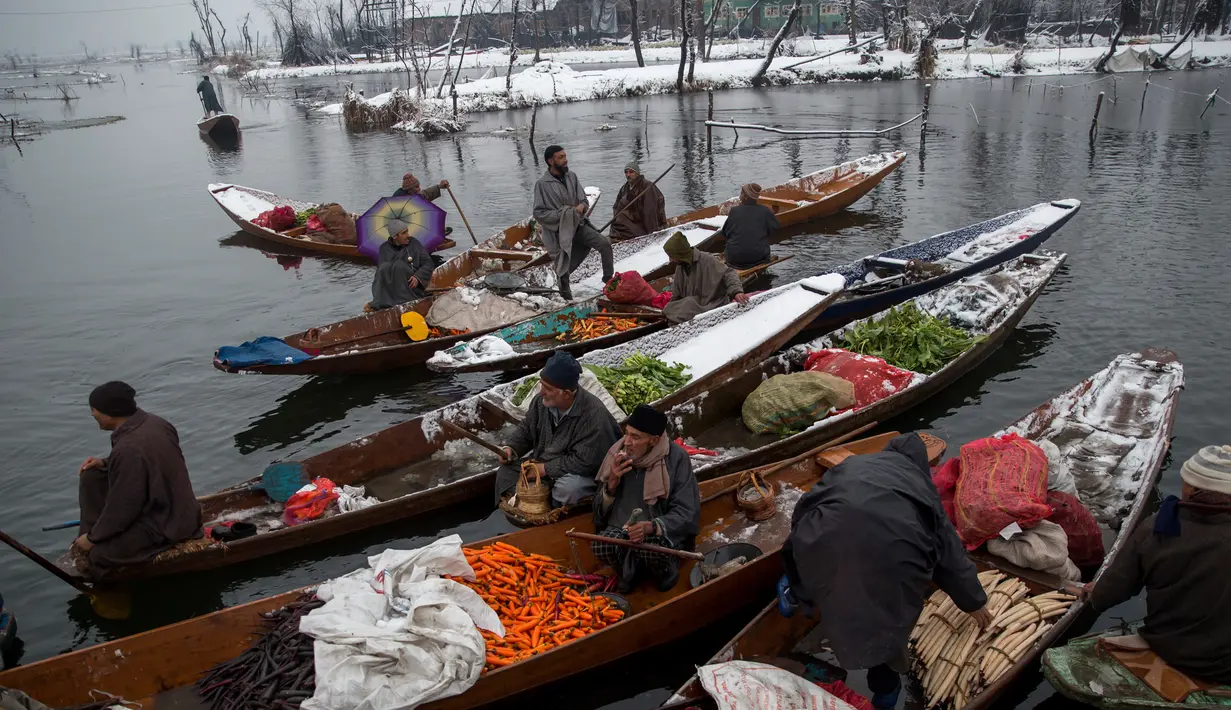Pedagang menjual sayur dan buah-buahan di pasar terapung di danau Dal, Srinagar, Kashmir India, (25/1). Dinginnya salju para pedagang ini tetap bersemangat menjajakan dagangannya di atas perahu. (AP Photo/Dar Yasin)