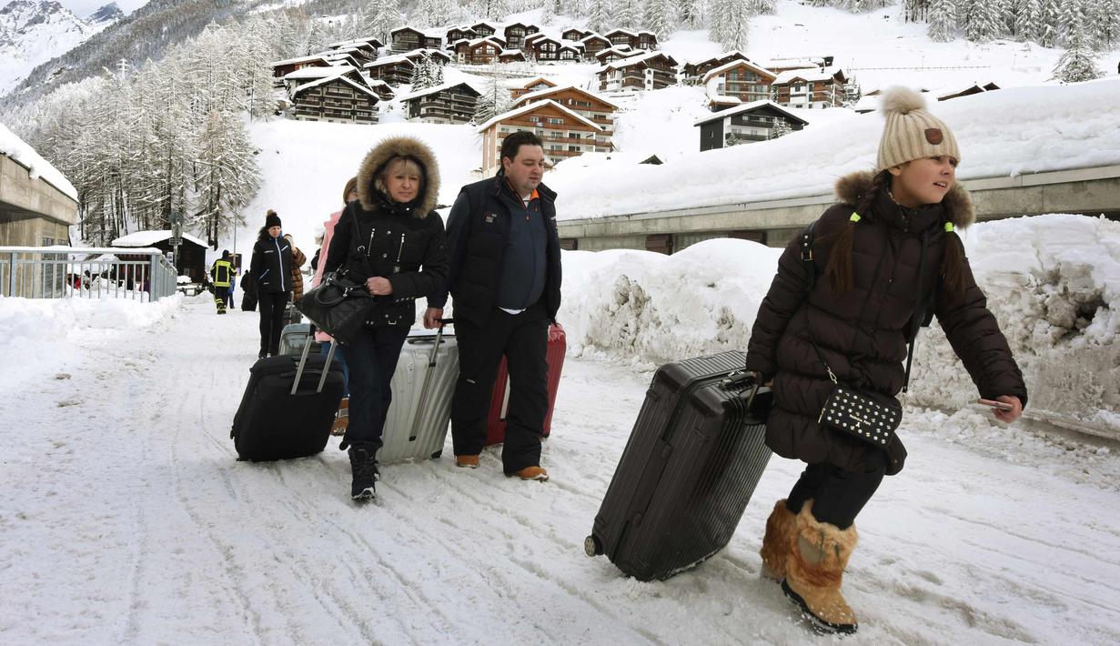 Sejumlah turis menuju heliport untuk dievakuasi dari Zermatt di Swiss (10/1). Pemadaman listrik di beberapa daerah lain, seperti di Kota Valais, juga terjadi akibat hujan salju lebat. (AFP Photo/Mark Ralston)