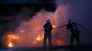 Petugas memadamkan api saat kerusuhan di bawah Menara Eiffel di dekat zona penggemar Paris sebelum laga Portugal vs Prancis di Final EURO 2016 di Prancis (10/6). Sejumlah fasilitas umum di sekitar Menara Eiffel rusak. (REUTERS/Stephane Mahe)