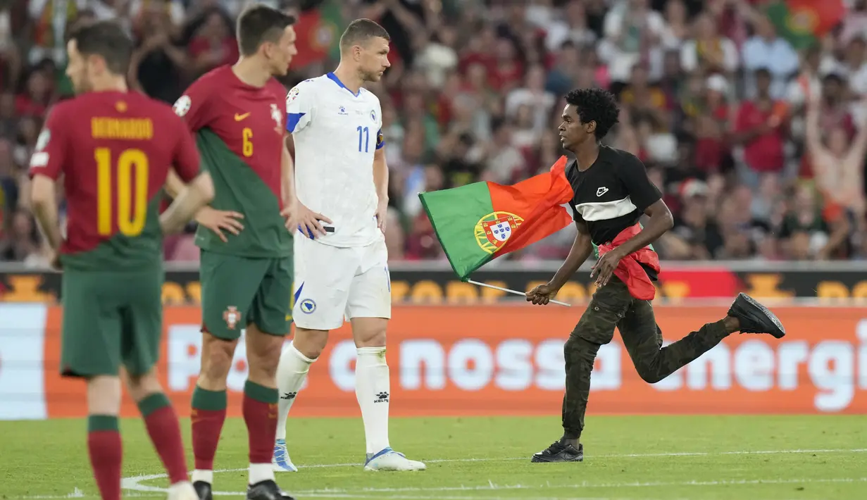 Ketika laga bergulir ada peristiwa menarik yang terjadi, yaitu seorang suporter menginvasi lapangan dengan membawa bendera Portugal. (AP Photo/Armando Franca)