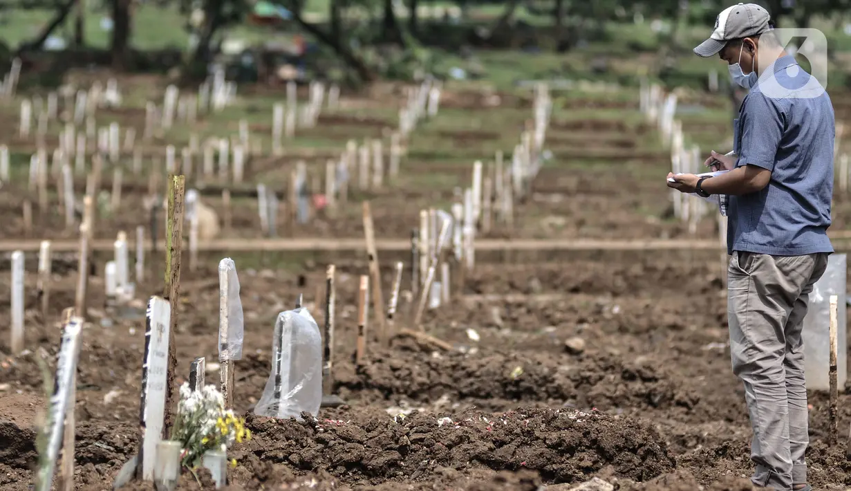 Petugas mendata makam pasien Covid-19 di TPU Bambu Apus, Jakarta, Selasa (2/3/2021). TPU Bambu Apus kini tidak lagi menampung pemakaman jenazah protokol Covid-19 akibat lahan di dua blok sudah penuh dan dialihkan ke TPU Srengseng Sawah. (merdeka.com/Iqbal S Nugroho)