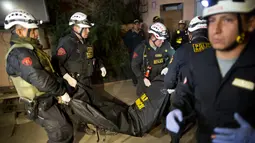 Petugas penyelamat membawa jenazah seorang turis setelah bus mengalami kecelakaan di Lima, Peru, (9/10). Pejabat Peru mengatakan sebuah bus wisata bersusun tidak terkendali dan berguling di jalan sempit di perbukitan. (AP Photo / Rodrigo Abd)