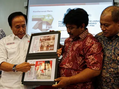 Direktur Filateli dan Properti PT Pos Indonesia, Tata Sugiarta (kiri) dan Ketua Panitia HUT PMI ke-70, Muhamad Muas (kedua kiri) menunjukan gambar perangko perayaan 70 tahun PMI di Museum Nasional, Jakarta,  Jumat (4/9/2015). (Liputan6.com/Yoppy Renato)