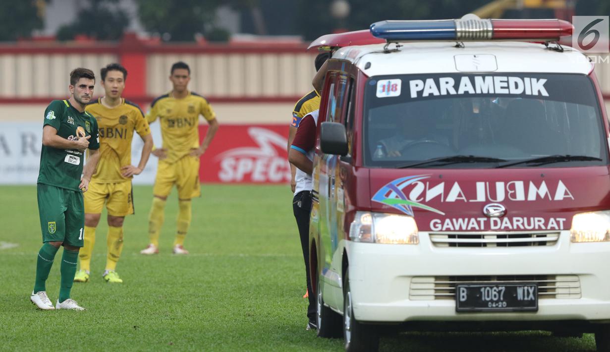 Ambulan mengevakuasi pemain Persebaya, Andri Muladi saat laga melawan Bhayangkara FC pada lanjutan Go-Jek Liga 1 Indonesia bersama Bukalapak di Lapangan PTIK, Jakarta, Rabu (11/7). Laga berakhir imbang. (Liputan6.com/Helmi Fthriansyah)