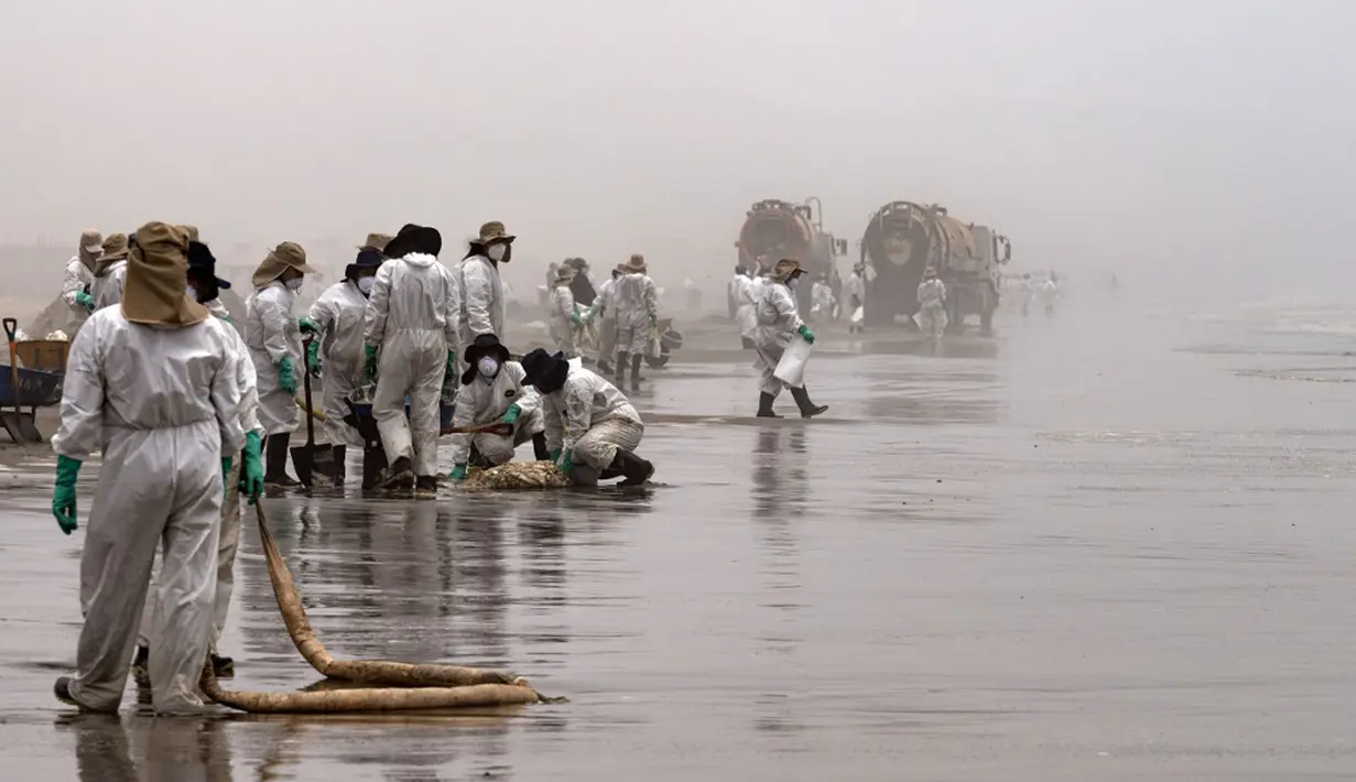 Petugas kebersihan bekerja untuk mengeluarkan minyak dari Pantai Cavero di Callao, Peru, 26 Januari 2022. Pembersihan Pantai Cavero dari tumpahan minyak kapal tanker Mare Doricum yang dihantam gelombang akibat letusan gunung berapi Tonga masih terus dilakukan. (Cris BOURONCLE/AFP)