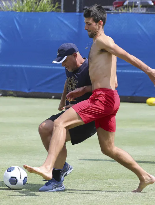 Petenis asal Serbia, Novak Djokovic berusaha merebut bola rekannya saat bermain sepakbola jelang bertanding melawan Cristian Garin dari Chile pada hari keenam turnamen tenis ATP Cup di Brisbane, Australia, Rabu (8/1/2020). (AP Photo/Tertius Pickard)