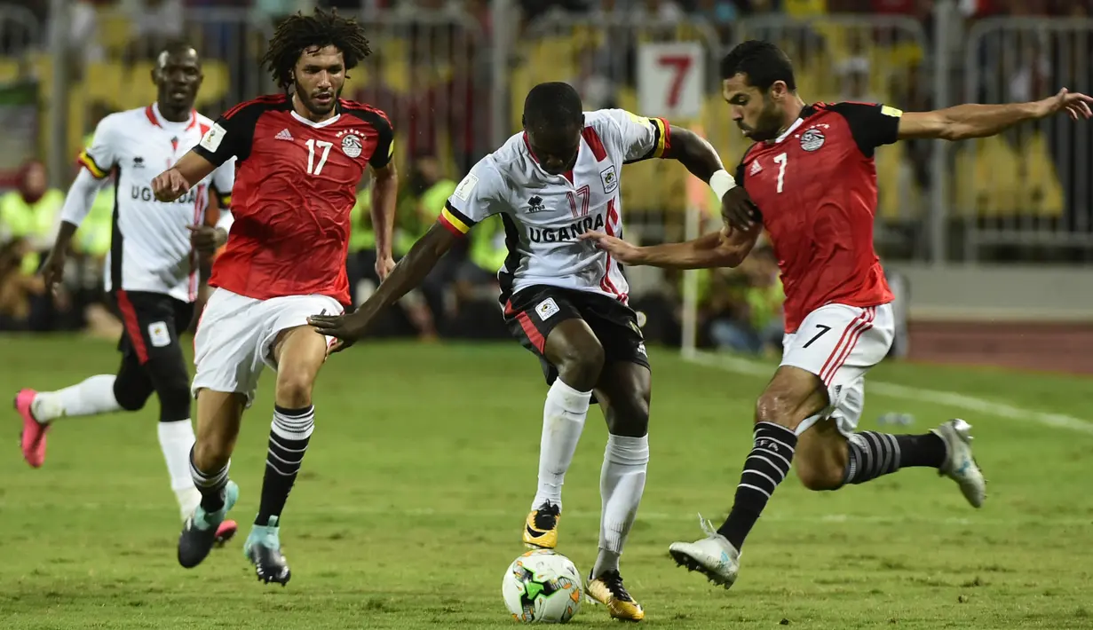 Pemain Mesir, Ahmed Fathy (kanan) dan Mohamed el-Nenny (kiri) mengadang laju pemain Uganda, Farouk Miya (tengah) pada laga kualifikasi Piala Dunia 2018 di Borg El Arab Stadium, Alexandria, Mesir (5/9/2017). Mesir menang 1-0. (AFP/Khaled Desouki)