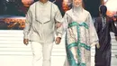 Fitri Tropica juga melenggang di runway koleksi Zaskia Sungkar bersama suaminya. Zaskia tampil dengan dress berkancing dengan warna abu-abu bercorak hijau dipadukan kerudung warna senada. Suaminya mengenakan baju koko lengan panjangnya. [@zaskiasungkar15]