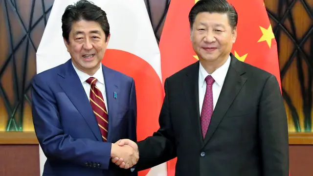 Perdana Menteri Jepang Shinzo Abe berjabat tangan dengan Presiden China Xi Jinping dalam sebuah pertemuan internasional (Kyodo News Agency)