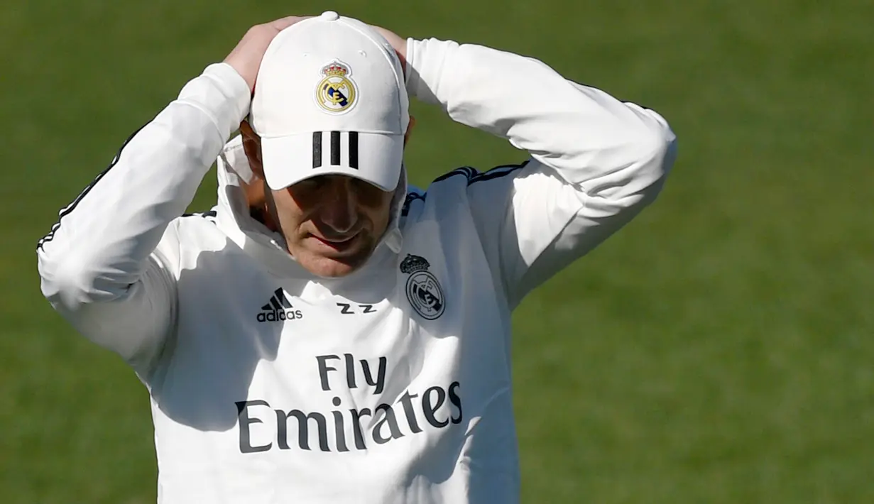 Pelatih Real Madrid Zinedine Zidane merapikan topinya saat menghadiri sesi pelatihan di fasilitas pelatihan Valdebebas di Madrid (15/3). Zidane kembali melatih Real Madrid menggantikan Santiago Solari. (AFP Photo/Gabriel Bouys)