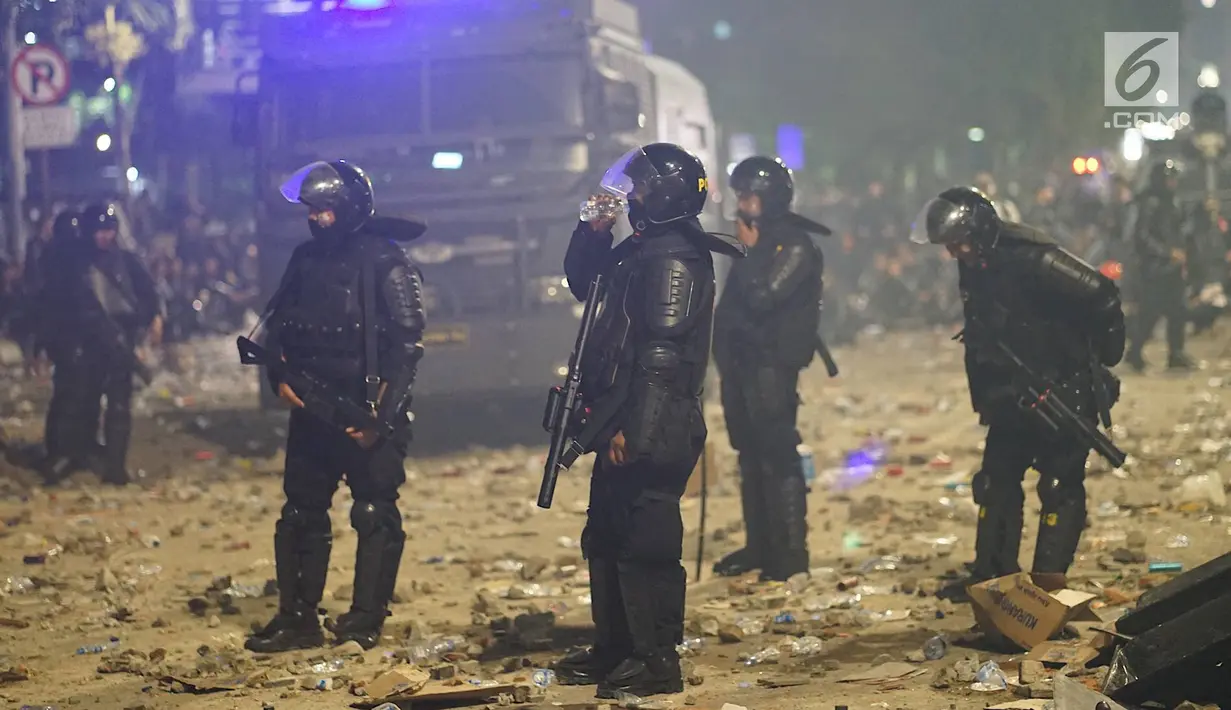 Personel Kepolisian dari satuan Brimob beristirahat sambil minum di sela-sela menghalau massa yang berlaku anarkis di sekitar depan Gedung Bawaslu, Jalan MH Thamrin, Jakarta, Rabu (22/5/2019). Aksi unjuk rasa yang dimotori GNKR berakhir ricuh. (Liputan6.com/Immanuel Antonius)