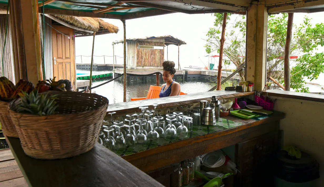 Seorang wanita menunggu di sebuah restoran di pulau buatan dari sampah plastik daur ulang di Abidjan, Pantai Gading pada Agustus 2019. Eric Becker asal Prancis membangun sebuah pulau terapung dari sekitar 700.000 sampah plastik daur ulang yang dikumpulkan di daerah sekitarnya. (ISSOUF SANOGO/AFP)