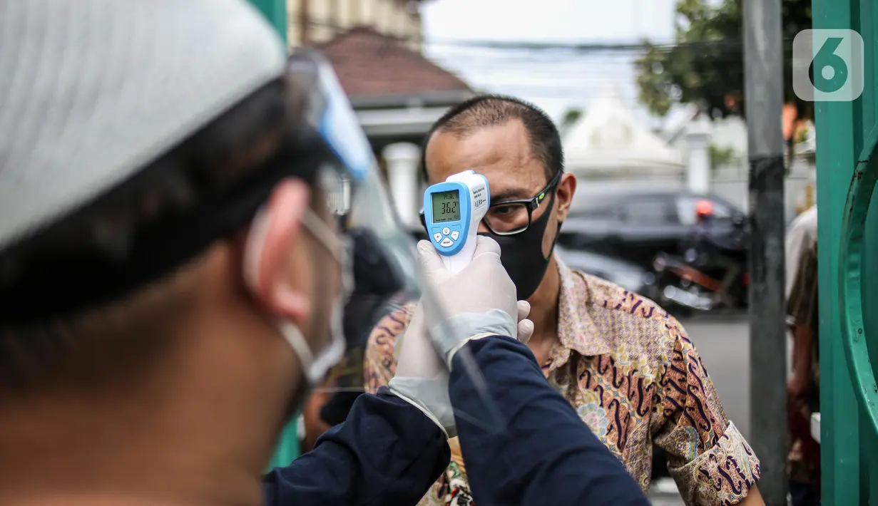 Petugas memeriksa suhu tubuh Jemaah sebelum memasuki Masjid Cut Meutia untuk salat Jumat di Jakarta Pusat, Jumat (5/6/2020). Masjid Cut Meutia kembali menyelenggarakan ibadah salat Jumat dalam masa PSBB transisi dengan menerapkan protokol kesehatan secara ketat. (Liputan6.com/Faizal Fanani)