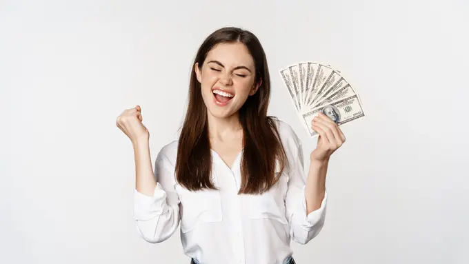 Seorang perempuan tampak bergembira sambil memegang sejumlah uang (Foto Dok: Freepik/benzoix)