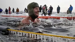 Seorang peserta tersenyum saat mengikuti kompetisi renang di perairan es di sungai Neva selama Big Neva Cup of Ice Swimming di St.Petersburg, Rusia, (4/3). (AP Photo/Dmitri Lovetsky)