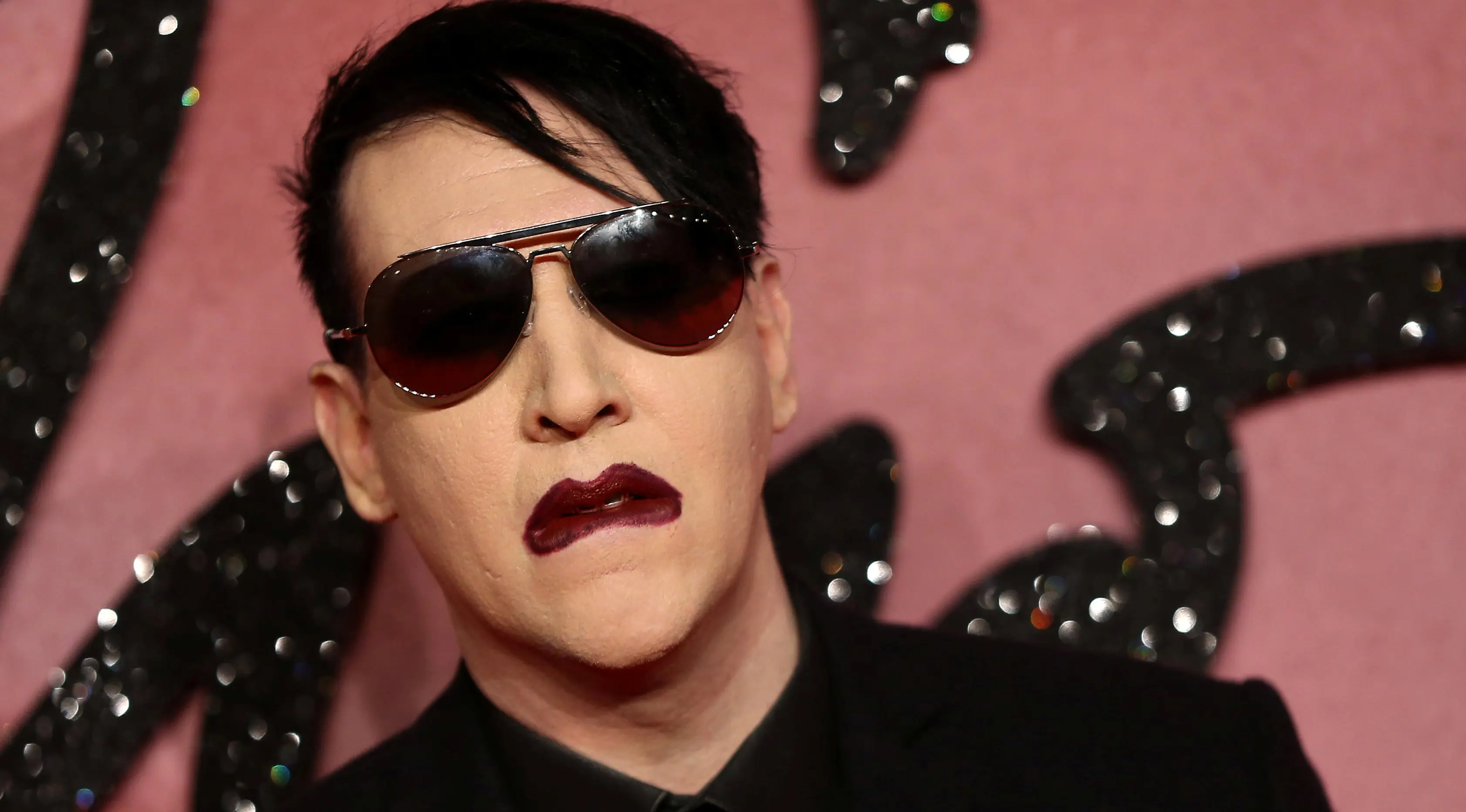 Pose Marilyn Manson saat menghidiri di Fashion Awards 2016 di London, Inggris (5/12). Mantan pacar Evan Rachel Wood tersebut tampil Fashionable dengan Jas dan kacamata hitam dengan gigi dan cincin ditangannya. (REUTERS/Neil Balai)