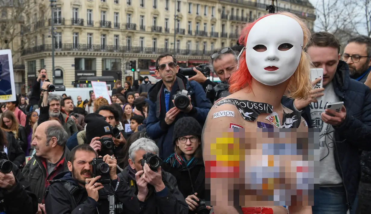Seorang aktivis menempelkan logo merek-merek internasional pada tubuhnya saat memperingati Hari Perempuan Internasional Place de la Republique, Paris, Jumat (8/3). (Alain JOCARD/AFP)