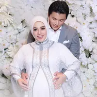 Syahrini memadukan penampilannya dengan hijab putih polos. Reino sendiri tampil gentleman mengenakan setelan jas dan celana panjang abu-abu, serta kemeja putih polos di baliknya. [Foto: Instagram/princessyahrini]