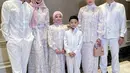 Ashanty tampil mengenakan kerudung pink dengan gaya lilit di bagian leher yang dimasukan ke dalam bajunya, dipadukan busana warna putih brokat. Sambil membawa tas Dior. [@ashanty_ash]