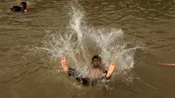 Seorang pria melompat ke sungai untuk mendinginkan tubuhnya saat cuaca panas yang ekstrem di Islamabad, Pakistan, (23/6/2015). Gelombang panas membuat warga Pakistan tak bisa jauh dari air untuk bertahan hidup. (REUTERS/Faisal Mahmood)