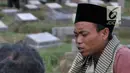 Seorang pria bernama Ma'ruf memimpin doa 'Talkin' untuk peziarah di TPU Kemiri, Rawamangun, Jakarta, Selasa (15/5). Pria yang bekerja sebagai guru ngaji ini bisa mendapatkan ratusan ribu rupiah dari hasil pembaca doa musiman. (Merdeka.com/Iqbal S Nugroho)