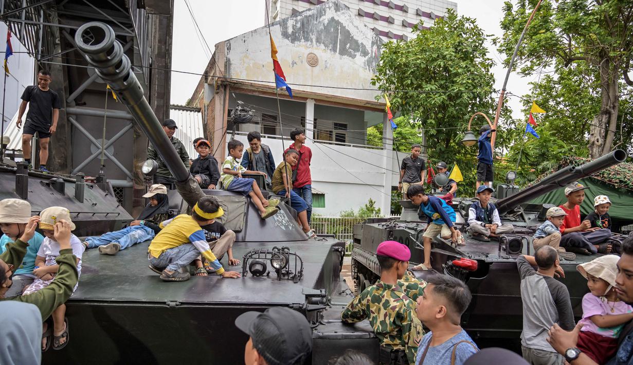 Orang-orang berfoto bersama kendaraan militer selama Pameran Marinir Indonesia, yang menandai peringatan Hari Ulang Tahun ke-80 Korps Marinir TNI AL di Surabaya, Jawa Timur pada Minggu 9 November 2025. Beberapa anak antusias menaiki kendaraan tempur milik Korps Marinir TNI AL yang dipamerkan di ruas jalan sekitar kawasan Gedung Negara Grahadi, Surabaya, Jawa Timur. (JUNI KRISWANTO/AFP)