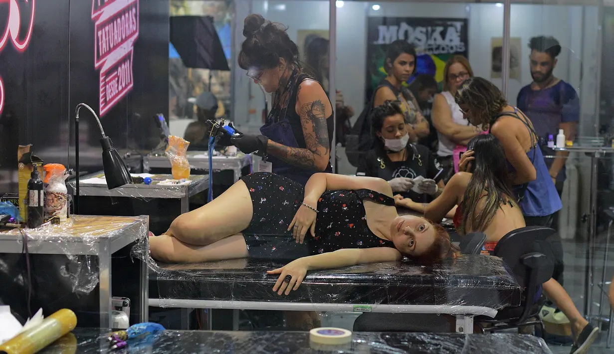 Seorang wanita bersiap ditato saat acara Tattoo Week tahunan di Rio de Janeiro, Brasil (12/1). Ajang perhelatan seniman dan penggemar tato ini diadakan setiap tahunnya di Brasil. (AFP Photo/Mauro Pimentel)