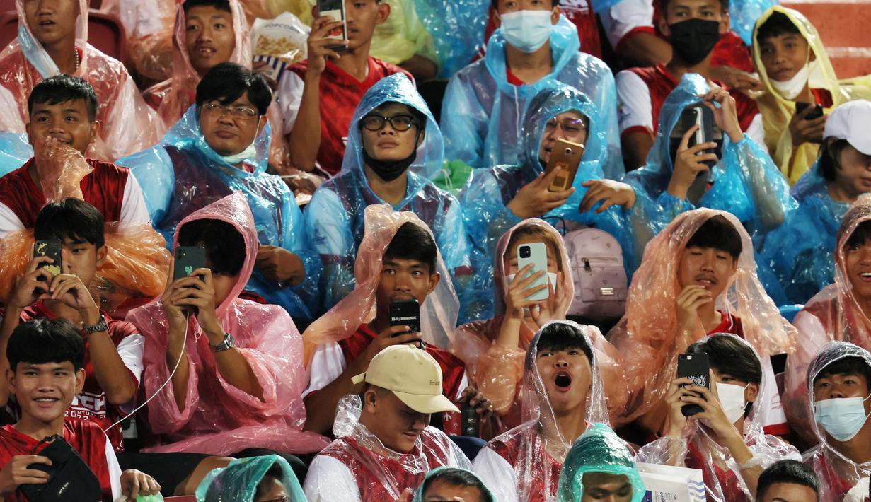 Sejumlah fans Liverpool menggunakan jas hujan saat menyaksikan sesi latihan The Reds di Stadion Rajamangala. (AFP/Jack Taylor)
