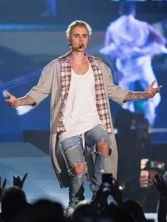 Penyanyi 22 tahun itu melompat-lompat di panggung yang basah sambil beratraksi di tengah percikan air, hingga membuatnya terpleset. (Bintang.com/AFP)