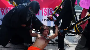 Sejumlah mahasiswa melakukan aksi menolak ISIS di Car Free Day, Bundaran HI, Jakarta, Minggu (15/3/2015). Mereka melakukan aksi teaterikal sebagai bentuk sindiran terhadap kekejaman ISIS. (Liputan6.com/Yoppy Renato) 