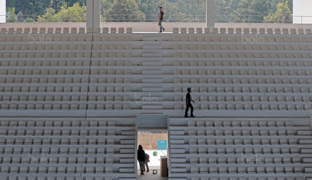 Pekerja merapikan kursi dan lantai Venue Aquatic Center di Senayan Sport Center, Jakarta (04/10/2017). Gedung dirancang semi terbuka. Atapnya tidak sepenuhnya menutupi bangunan, sehingga cahaya bisa masuk dengan leluasa. (Bola.com/Nicklas Hanoatubun)