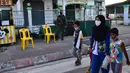 Seorang wanita yang mengenakan masker berjalan bersama anak-anak saat membeli makanan di pasar menjelang berbuka puasa selama bulan suci Ramadan di Provinsi Narathiwat, Thailand, Selasa (5/5/2020). Ramadan kali ini berlangsung di tengah bayang-bayang virus corona COVID-19. (Madaree TOHLALA/AFP)