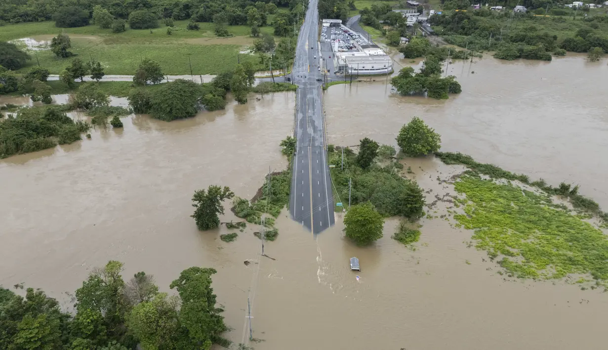 Sungai La Plata membanjiri jalan setelah Badai Tropis Ernesto melewati Toa Baja, Puerto Rico, Rabu (14/8/2024). (AP Photo/Alejandro Granadillo)