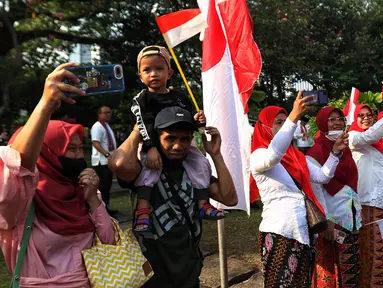 Masyarakat menyaksikan proses kirab budaya di sepanjang area Monumen Nasional (Monas) di Jakarta, Kamis (17/8/2023). Pasukan kirab sendiri diikuti peserta dari beragam elemen masyarakat, mulai pelajar hingga ibu-ibu berkebaya. (Liputan6.com/Angga Yuniar)