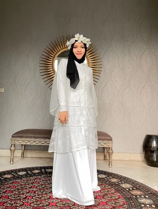 Inspirasi baju Lebaran dari Sajidah Halilintar. Ia mengenakan gamis cantik berwarna putih, dipadukannya dengan hijab hitam polos, dan hiasan kepala berbentuk bunga sebagai pemanis penampilannya secara keseluruhan. [Foto: Instagram/sajidahhalilintar]