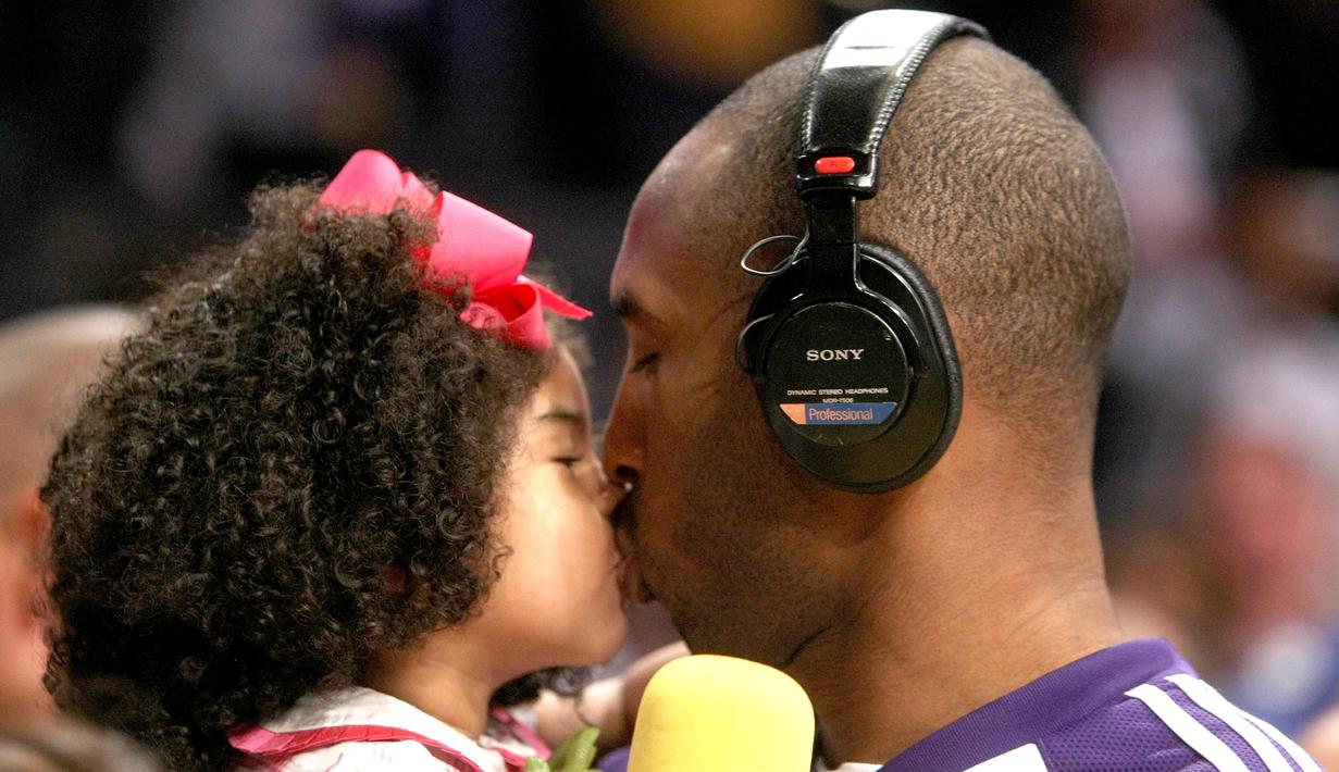 Pebasket LA Lakers, Kobe Bryant, mencium putrinya Gianna sebelum melawan Memphis Grizzlies pada laga NBA di Staples Center, Los Angeles, Jumat (12/4/2009). (AFP/Stephen Dunn)