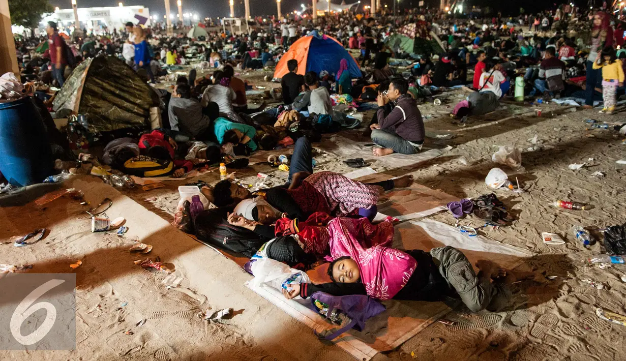 Sejumlah beristirahat usai menyaksikan atraksi kembang api pergantian tahun di Pantai Lagoon , Ancol, Jakarta, Minggu (1/1). Warga dari berbagai daerah sekitar Jakarta memilih menghabiskan malam tahun baru di kawasan Ancol.  (Liputan6.com/Gempur M. Surya)