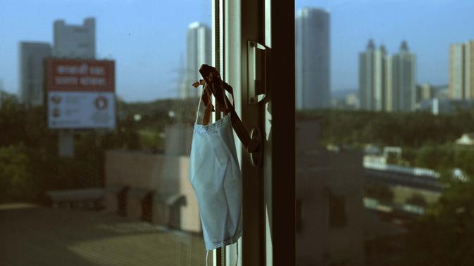 Masker fotografer Associated Press Rafiq Maqbool tergantung pada jimat keberuntungan yang dibuat oleh putrinya di sebuah kamar hotel tempat dia dikarantina, Mumbai, India, 23 April 2020. Maqbool harus meninggalkan istri dan anak-anaknya untuk menjalani karantina. (AP Photo/Rafiq Maqbool)