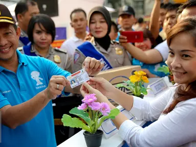 Kapolda Metro Jaya, Irjen Pol Tito Karnavian (kiri) memberikan SIM A yang telah selesai secara online kepada warga dalam rangka HUT Polantas yang ke-60 di Bundaran HI, Jakarta, Minggu (27/9/2015). (Liputan6.com/Faizal Fanani)