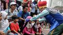 Badut yang tergabung dalam Aku Badut Indonesia mengajak bermain seorang anak saat car free day di Bunderan HI, Jakarta, Minggu (9/12). Aksi tersebut bentuk kampanye positif bertujuan mengajak masyarakat peduli terhadap sesama. (Liputan6.com/Faizal Fanani)