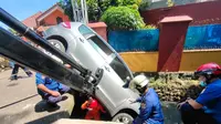 Petugas Damkar mengevakuasi mobil yang terpersok ke selokan di Jalan Pembaharuan, Kelapa Dua Wetan, Ciracas, Jakarta Timur. (Sudin Gulkarmat Jaktim)