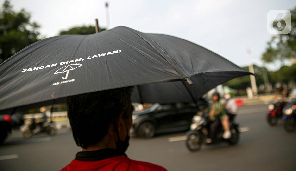 Anggota Jaringan Solidaritas Korban untuk Keadilan (JSKK) menggunakan payung hitam bertuliskan "Jangan Diam, Lawan!" saat melakukan Aksi Kamisan ke-795 di seberang Istana Merdeka, Jakarta, Kamis (16/11/2023). (Liputan6.com/Faizal Fanani)
