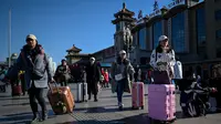 Penumpang berjalan dengan membawa tas menuju pintu masuk stasiun kereta api Beijing di ibu kota China, Senin (21/1). Sebagian warga China yang tinggal di kota-kota besar mulai mudik untuk merayakan tahun baru Imlek bersama keluarga. (WANG ZHAO/AFP)