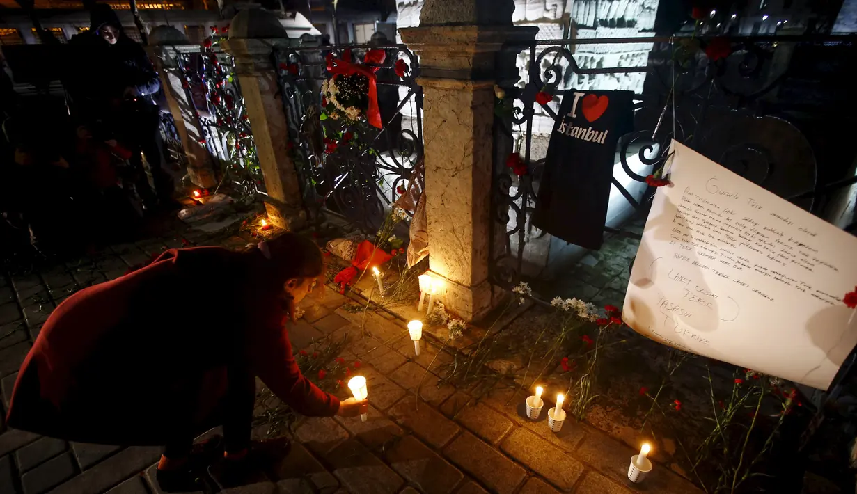 Seorang wanita meletakkan lilin di lokasi bom bunuh diri di Sultanahmet Square, Istanbul, Rabu (13/1). Bunga dan lilin tersebut wujud belasungkawa untuk korban ledakan di Turki. (REUTERS/Osman Orsal)