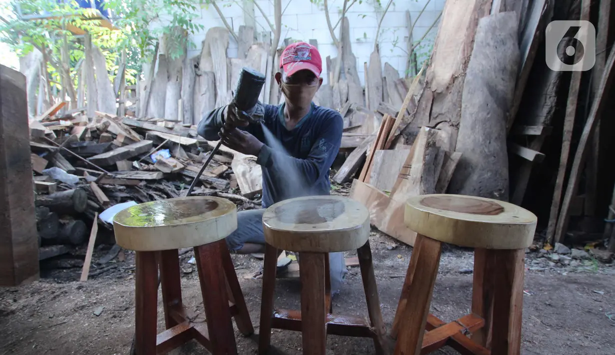 Perajin menyelesaikan pembuatan kursi dari kayu bekas di Pinang, Kota Tangerang, Banten, Minggu (28/3/2021). Furnitur berbahan dasar kayu bekas tersebut dijual dari harga Rp50.000 hingga lima juta rupiah dan dipasarkan hingga ke Sumatera dan Kalimantan. (Liputan6.com/Angga Yuniar)